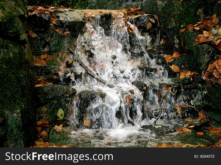 Waterfall in stream with autumn leaves