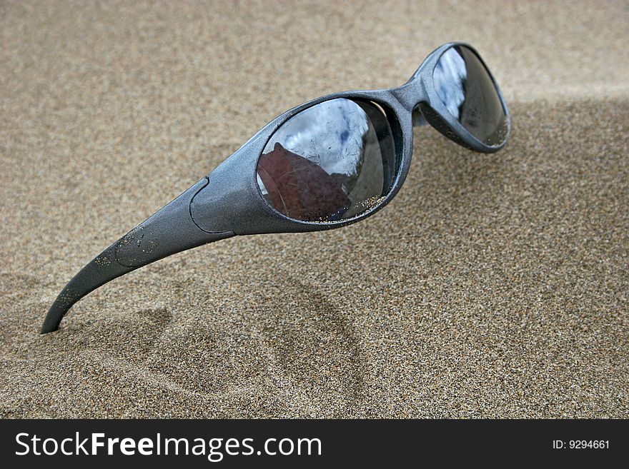 Pair of sunglasses on sandy beach