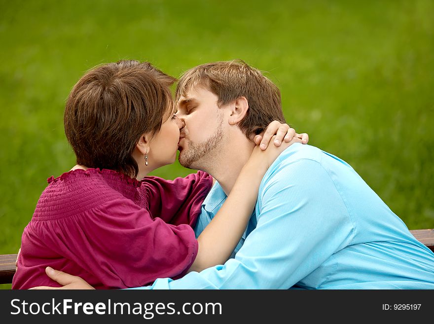 The happy adult couple kisses in park