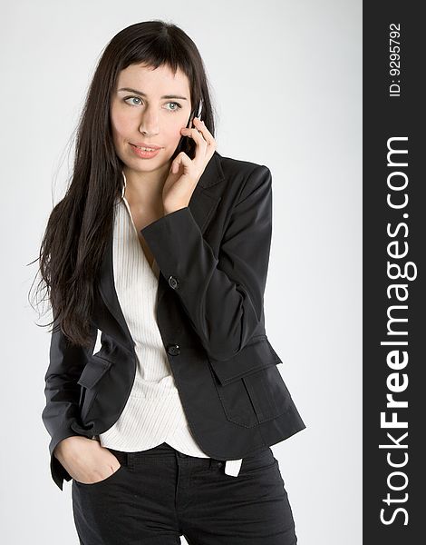 Young business woman with mobile phone on gray background