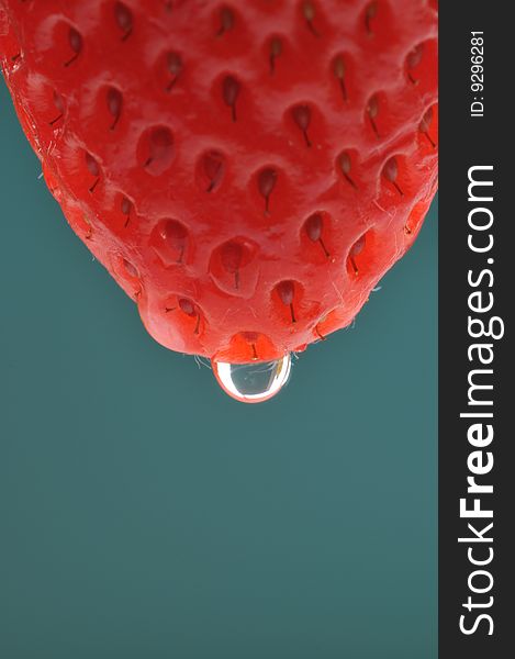 Strawberry with a drop on green background