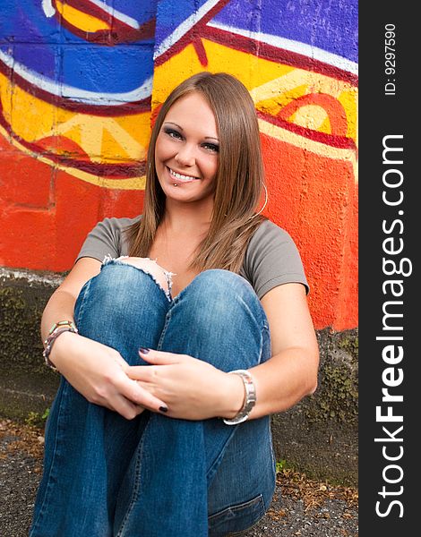 Portrait of young woman sitting on the floor outdoors and looking at camera. Portrait of young woman sitting on the floor outdoors and looking at camera