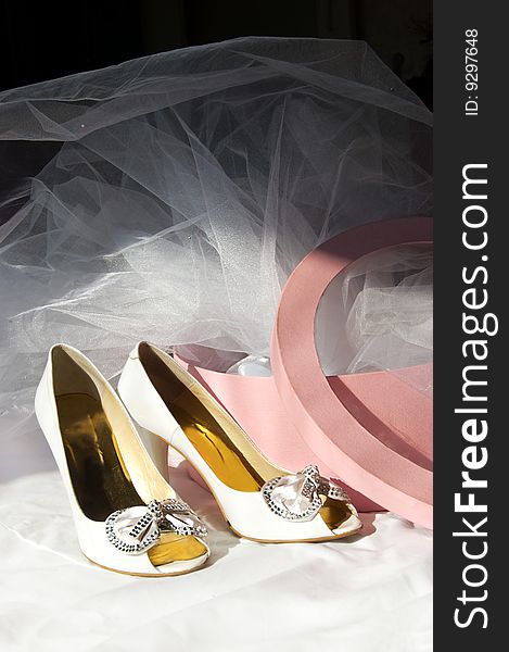 Wedding shoes, box and veil over dark background
