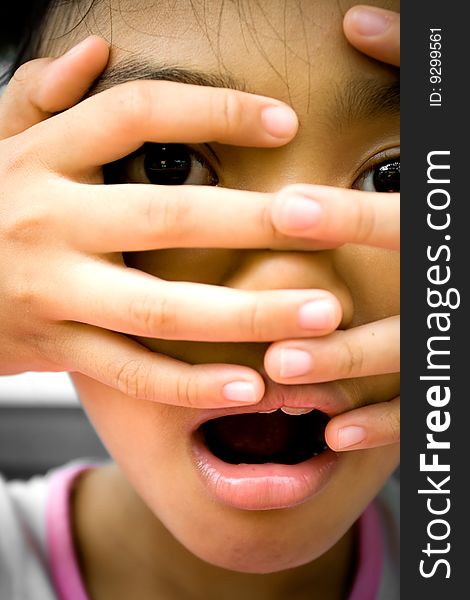 Little girl looks surprised and terrified onto something she saw. putting her fingers over her face. Little girl looks surprised and terrified onto something she saw. putting her fingers over her face.