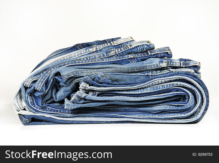 Stack of washed-out folded blue jeans isolated on white. Stack of washed-out folded blue jeans isolated on white