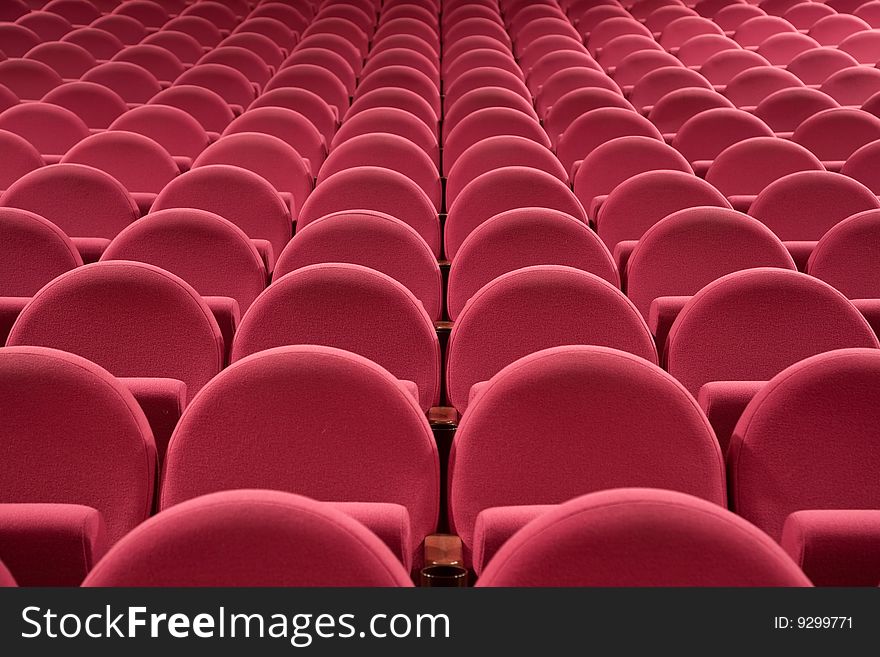 Close-up of empty cinema auditorium with line of pink chairs.