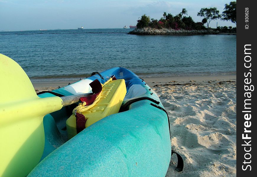 Holiday resort area with a kayak or ocean canoe, sidelit by the setting sun at 6pm, emphasis on what can be explored. Holiday resort area with a kayak or ocean canoe, sidelit by the setting sun at 6pm, emphasis on what can be explored