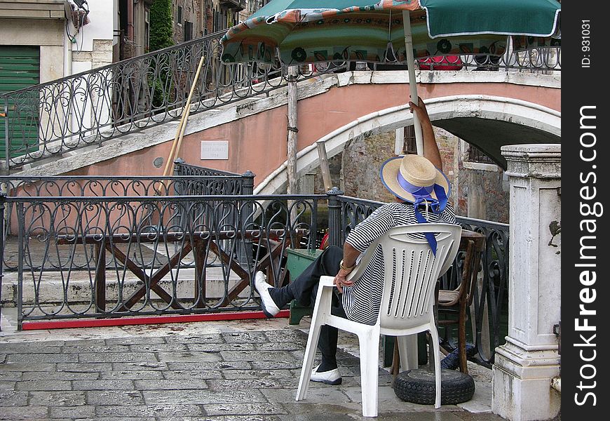 A venetian gondolier sitting and waiting for tourists. A venetian gondolier sitting and waiting for tourists