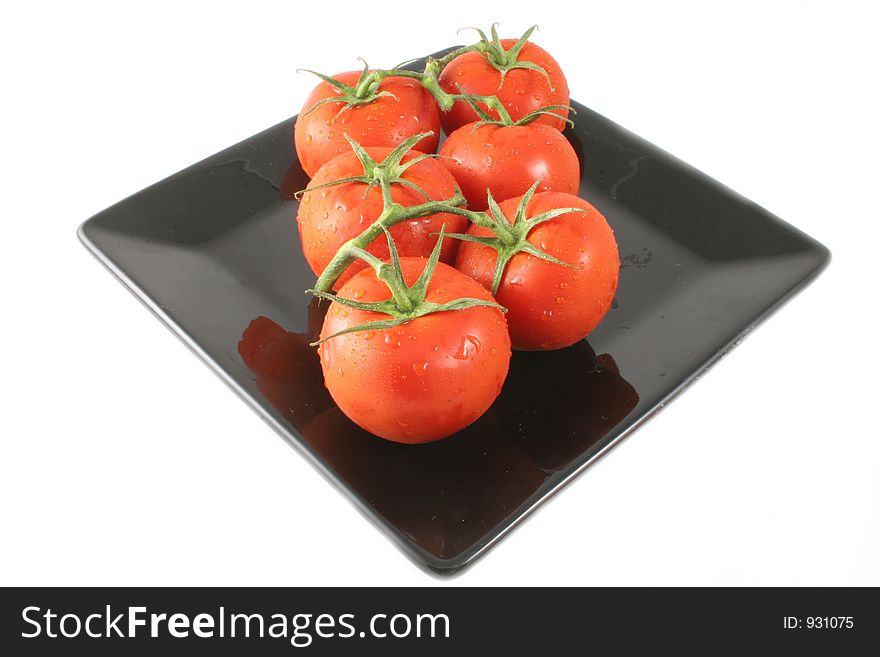 Vine Tomatoes Isolated on a black plate presented diagonally