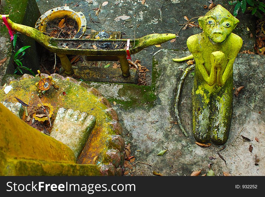 Monkey begs Buddha depiction at Wat in Surat Thani, Thailand.