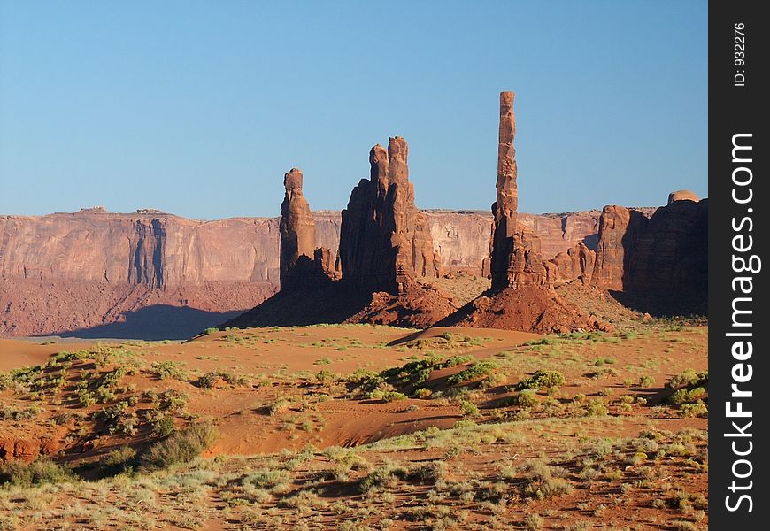 Mesa cliff walls, pinnacles, sand and sagebrush in Monument Valley in the late afternoon. Mesa cliff walls, pinnacles, sand and sagebrush in Monument Valley in the late afternoon.