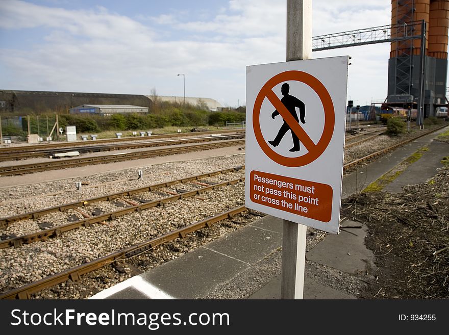 The edge of a platform at a British railway station, the train track behind, and a no entry sign reading Passengers must not pass this point or cross the line. The edge of a platform at a British railway station, the train track behind, and a no entry sign reading Passengers must not pass this point or cross the line.