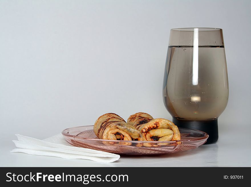 Rolled pancakes with sweet strawberry jam and glass of fresh mineral cool water. Rolled pancakes with sweet strawberry jam and glass of fresh mineral cool water