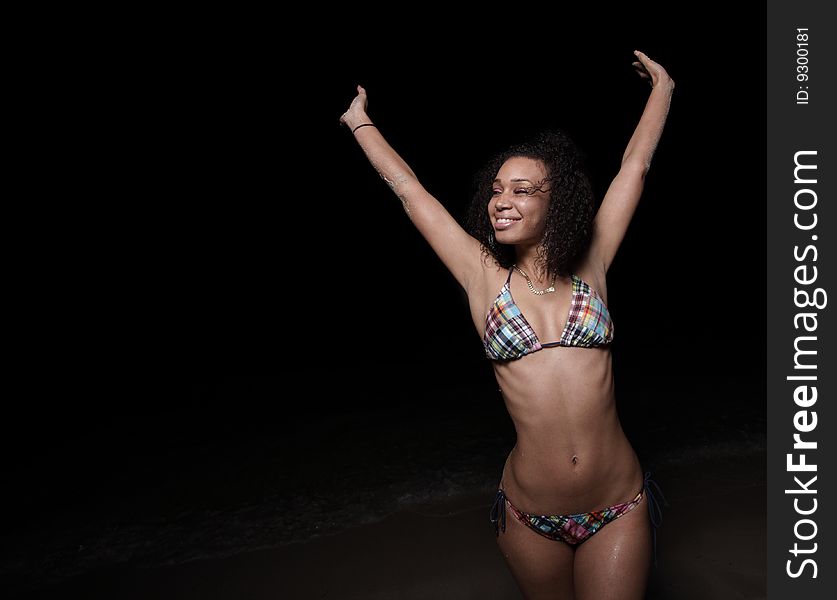 Joyous woman in a bikini extending her arms upward