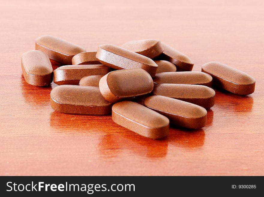 Brown pills over wood texture. Medicine image