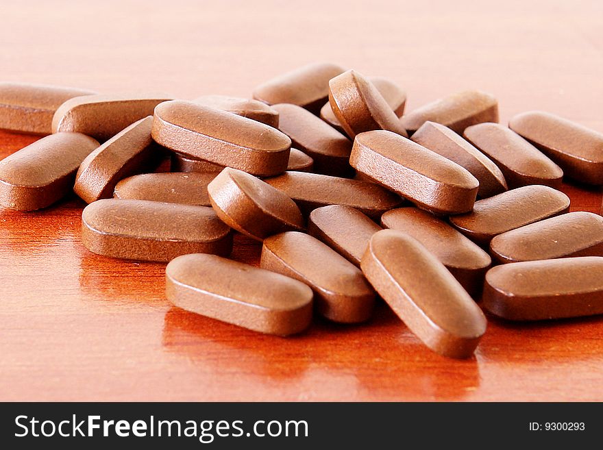 Brown pills over wood texture. Medicine image