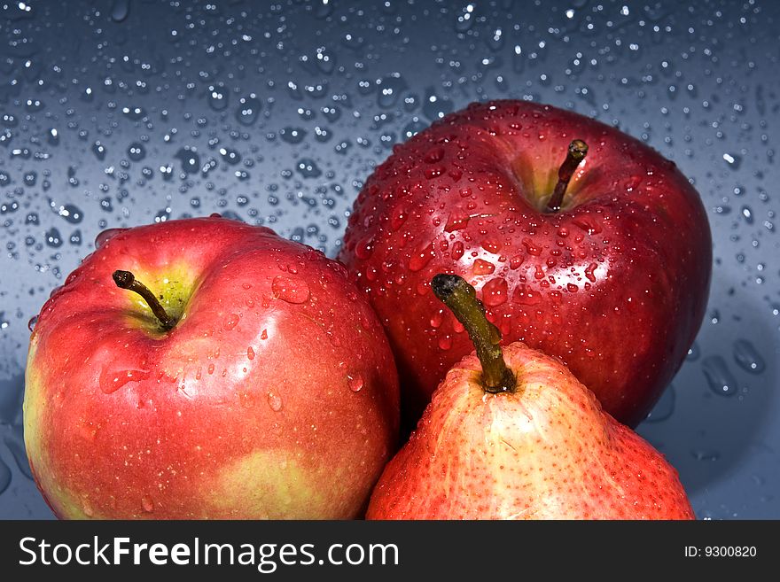 Two Apples And Pear On A Grey Wet Background.