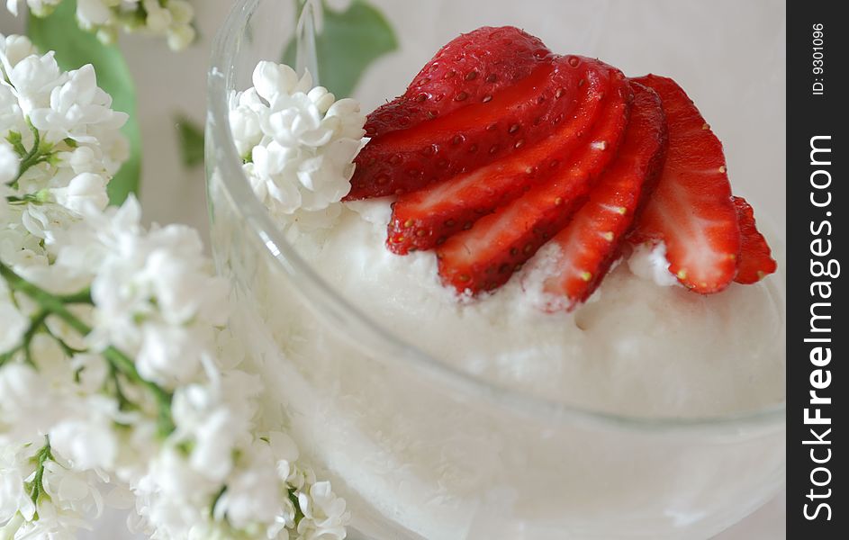 Milk frozen decorated by a strawberry and branch of white lilac. Milk frozen decorated by a strawberry and branch of white lilac
