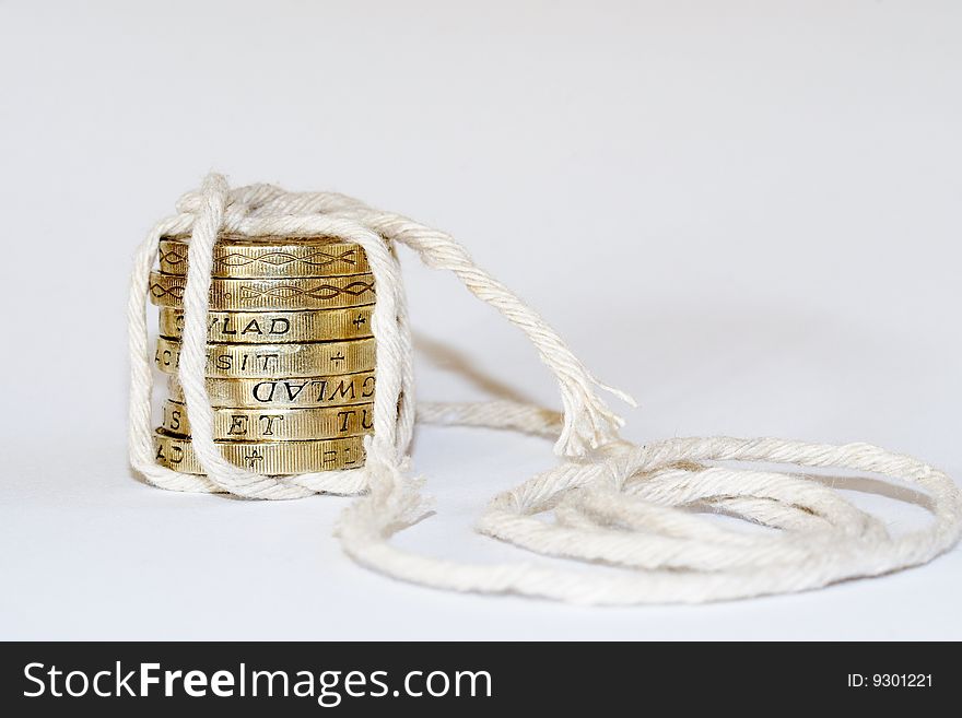 A close up photo of English one pound coins tied with string implying money tied up