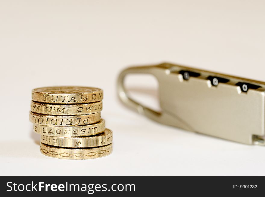 A close up photo of English one pound coins with a lock implying money locked in.