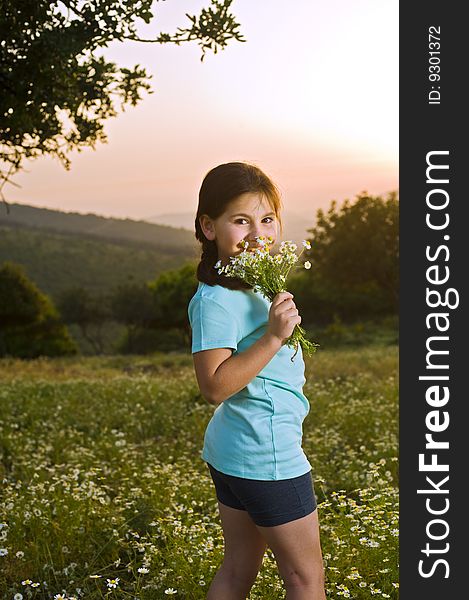 Girl holding flowers in field at sunset
