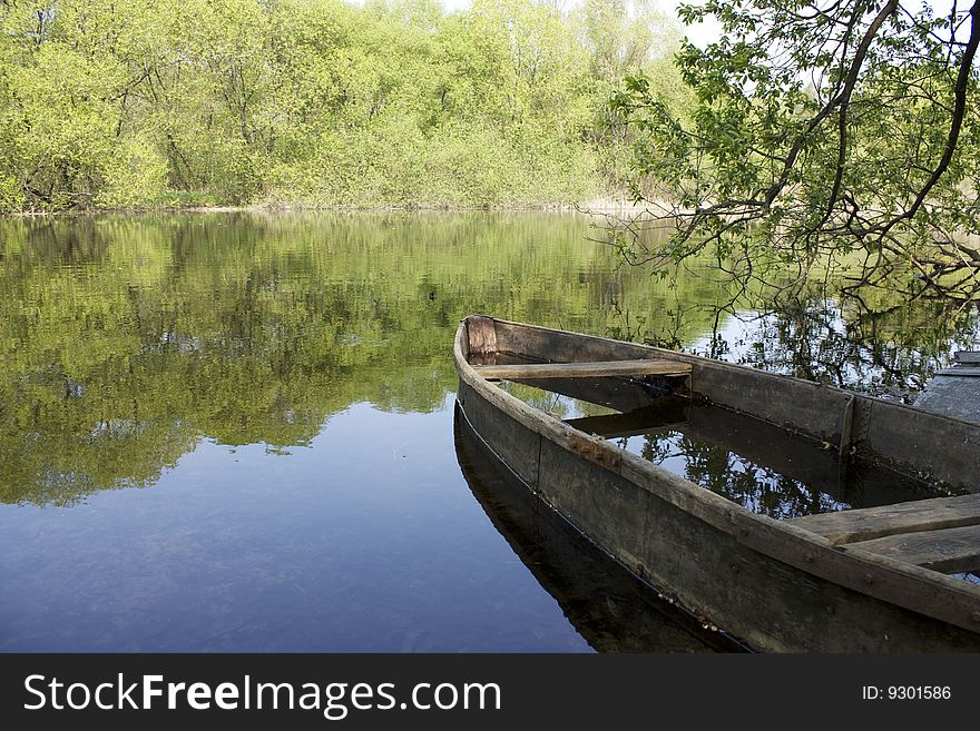 On the image there is old boat and river landscape.
