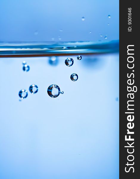 Bubbles in a glass of water on a blue background . Bubbles in a glass of water on a blue background .