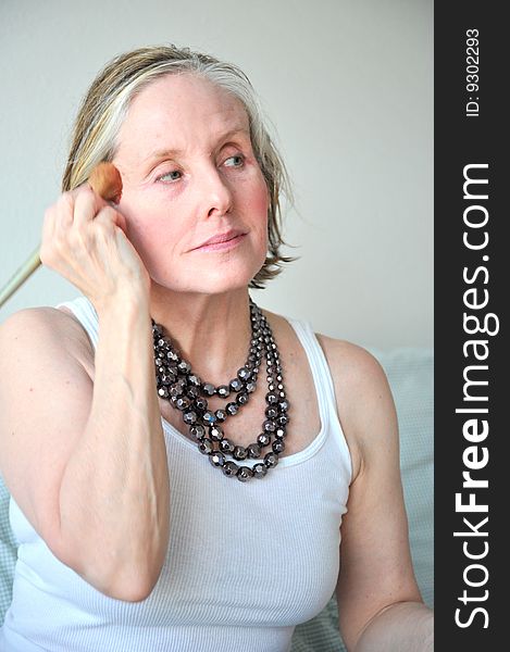 Mature female beauty applying makeup.