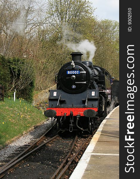 A steam train pulling up against the platform