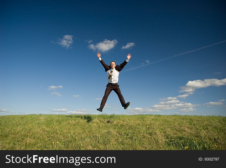 Jumping Businessman in meadow - green grass and blue sky. Jumping Businessman in meadow - green grass and blue sky