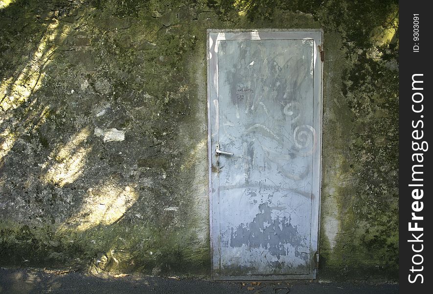 A wooden door in a dark damp alley. A wooden door in a dark damp alley.