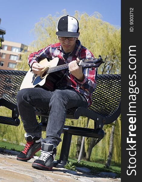 Young Man Playing Guitar In Park