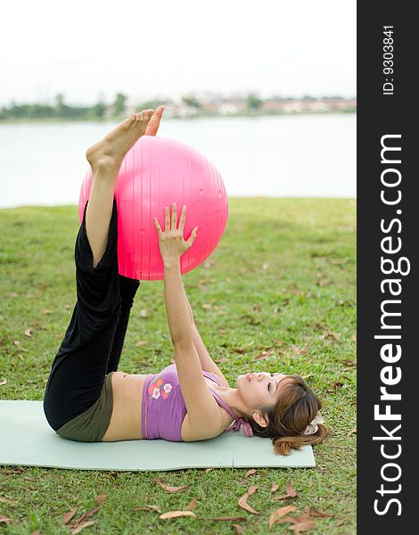 An asian female exercising with an exercise ball. An asian female exercising with an exercise ball.