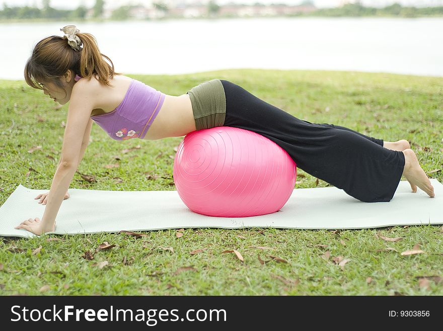 An asian female exercising with an exercise ball doing assisted pushups. An asian female exercising with an exercise ball doing assisted pushups.