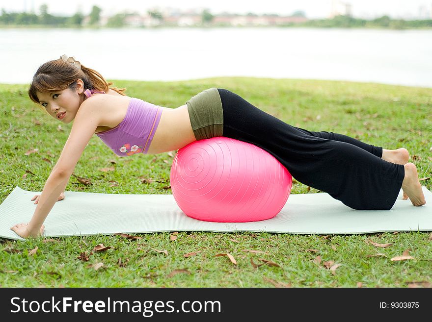 An asian female exercising with an exercise ball doing assisted pushups. An asian female exercising with an exercise ball doing assisted pushups.