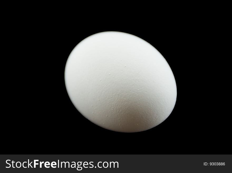 A plain white egg isolated on a black background. A plain white egg isolated on a black background