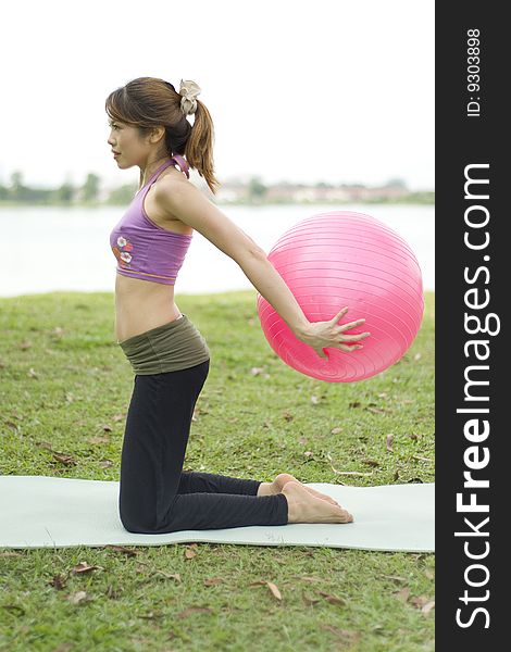 An asian female exercising with an exercise ball strengthening posture. An asian female exercising with an exercise ball strengthening posture.