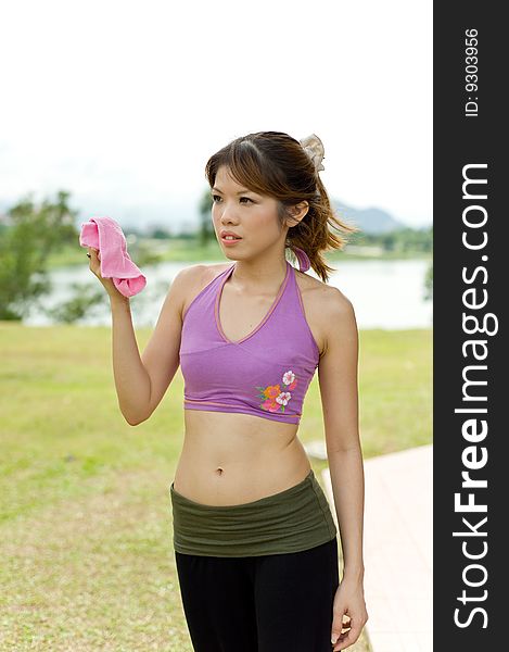 An asian lady posing with a pink towel used to wipe sweat during exercise. An asian lady posing with a pink towel used to wipe sweat during exercise.