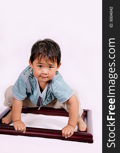 A picture of a little chinese boy squatting on a frame. A picture of a little chinese boy squatting on a frame