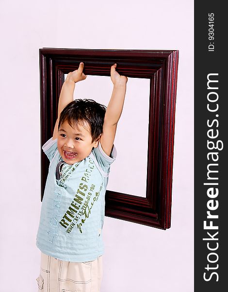 A picture of a little chinese boy holding a frame high up and laughing cheerfully. A picture of a little chinese boy holding a frame high up and laughing cheerfully