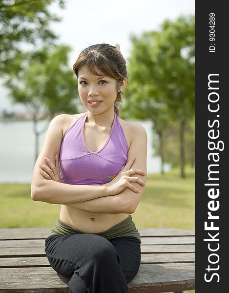 An asian female is resting on a bench quite happy with herself. An asian female is resting on a bench quite happy with herself.