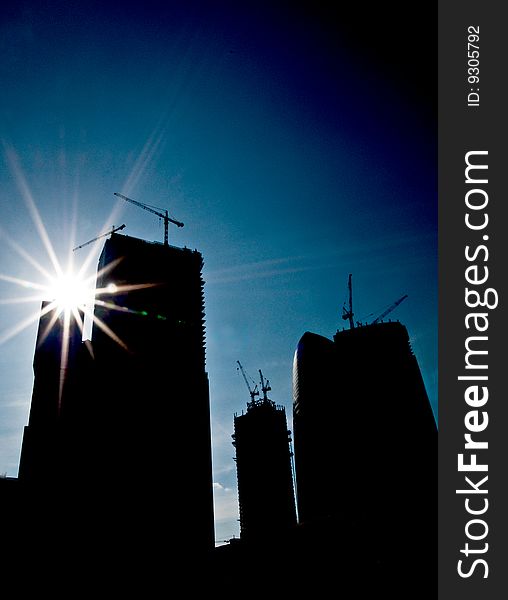 Silhouettes of skyscrapers being built on a background of dark blue sky