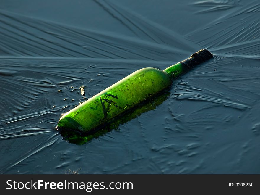 A green wine bottle in frozen water. A green wine bottle in frozen water