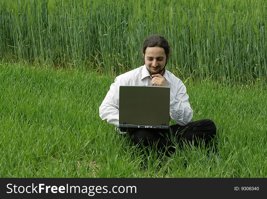 A man sitting on a field and works. A man sitting on a field and works