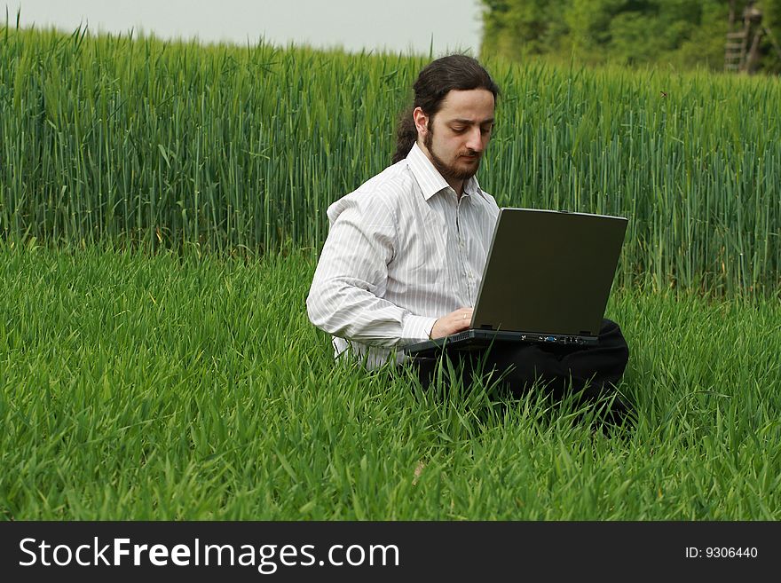 A man sitting on a field and works. A man sitting on a field and works
