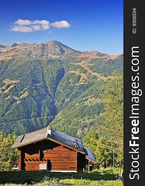 A Swiss alpine chalet with a magnificent view looking out over a valley in the Alps. Space for text in the clear blue sky. A Swiss alpine chalet with a magnificent view looking out over a valley in the Alps. Space for text in the clear blue sky.