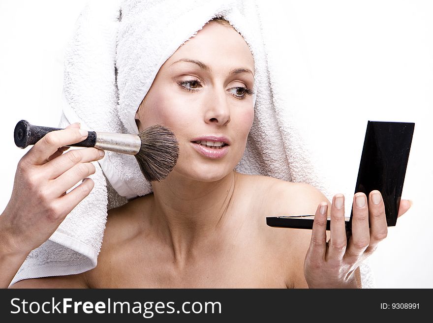 Happy woman in towel doing her makeup using brush and mirror. Happy woman in towel doing her makeup using brush and mirror