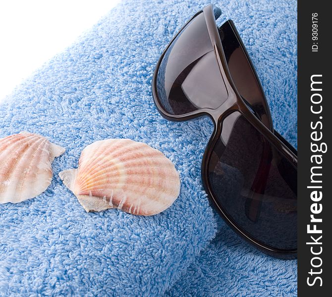 Towel, shells, sunglasses closeup on white background
