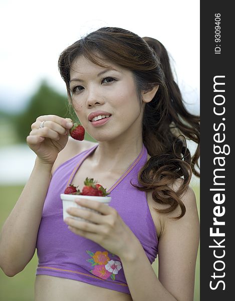 An asian lady taking a break enjoying a bowl of healthy strawberries. An asian lady taking a break enjoying a bowl of healthy strawberries.