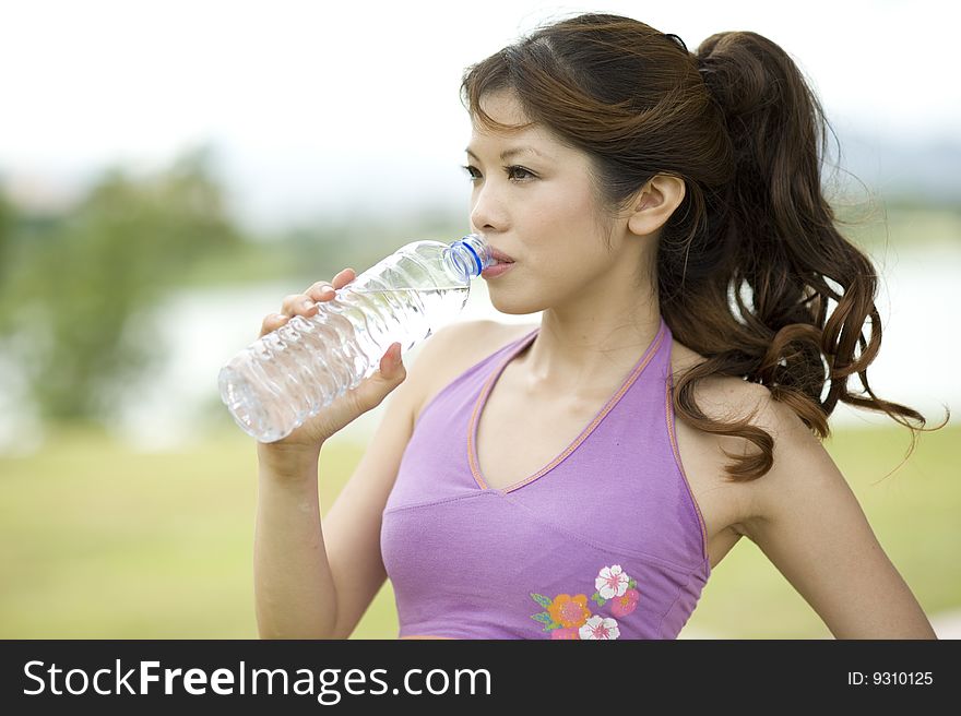 An asian female cooling off by drinking water. An asian female cooling off by drinking water.